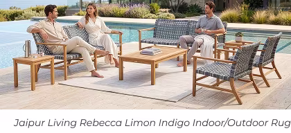 Three people lounge on woven outdoor sofas arranged over a large off-white rug by a pool. Image Text: Jaipur Living Rebecca Limon Indigo Indoor/Outdoor Rug