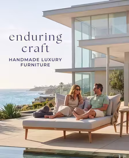 Couple relaxing on a luxury outdoor daybed beside a coastal pool.