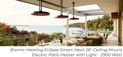 Three hanging patio heaters above a coastal outdoor dining table and lounge area.